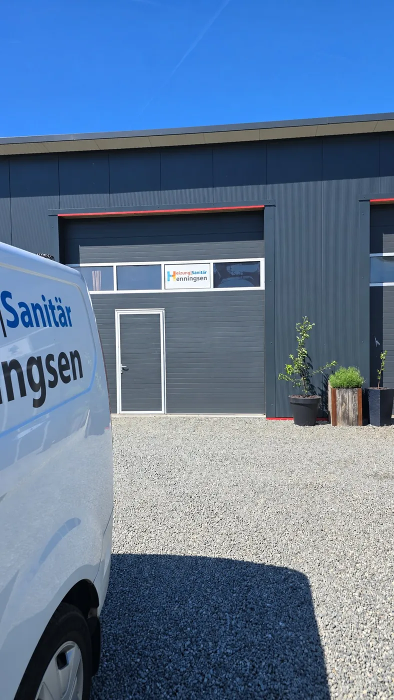 Betriebsstandort von Heizung-Sanitär-Henningsen mit Firmenschild und Firmenwagen
