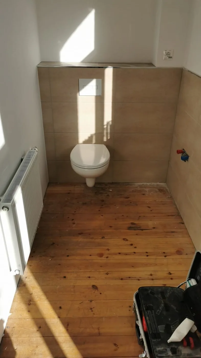 Zwischenstand einer Badsanierung mit wandhängendem WC und vorbereiteten Waschtischanschlüssen