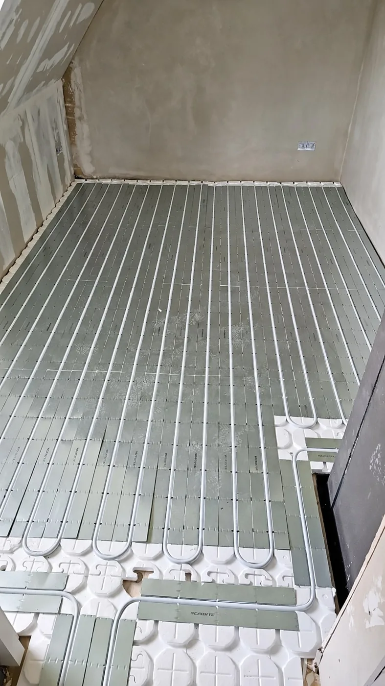 Fußbodenheizung im Trockenbausystem mit weißen Rohren und Wärmeleitblechen